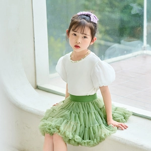 Detail of girls' fluffy layered green mesh tutu skirt paired with white puff sleeve top