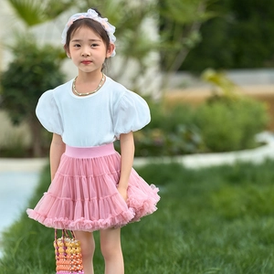 Detailed outdoor shot of girls pink tiered tutu skirt with white puff sleeve top