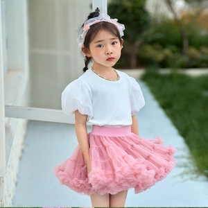 Detail of girls white puff sleeve top and layered pink mesh tutu skirt in outdoor setting