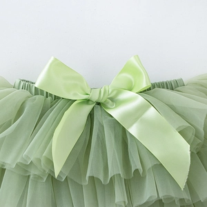 Détail d'une jupe tutu en tulle vert clair pour bébé avec un grand nœud en satin