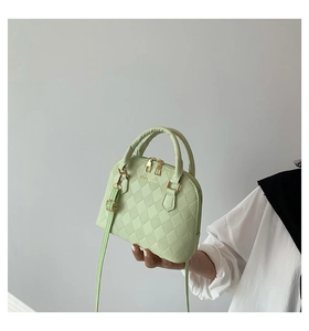 Detail of light green quilted shell bag with metallic gold hardware and handles