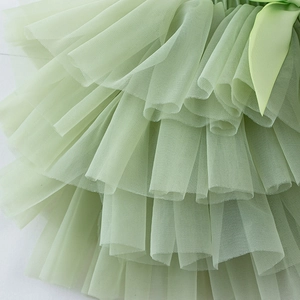 Détail macro de la jupe tutu multicouche vert sauge avec un nœud décoratif en satin