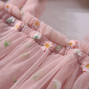 Détail de la robe en tulle rose avec broderie de marguerites et volants délicats