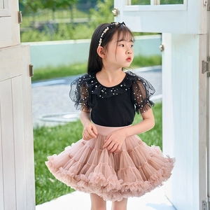 Detail of girls' black sequined sleeve top and layered pink mesh tutu skirt in outdoor setting
