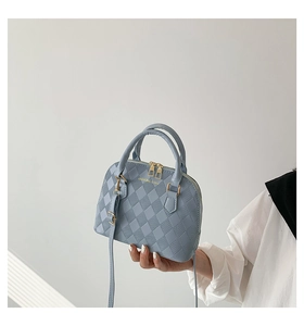 Detail of light blue quilted shell bag showing gold metal hardware and brand logo