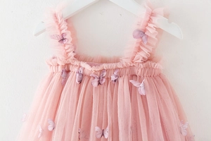 Detailed close-up of pink tulle dress featuring 3D purple butterfly appliques and sequins