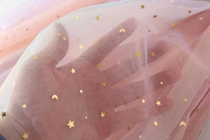 Detail of pink mesh fabric with gold star and moon sequins for girls' tulle dress