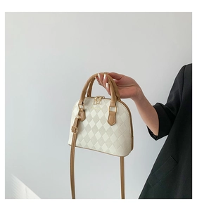 Detail of quilted beige and brown shell bag with gold zippers and adjustable strap