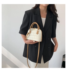 Quilted white shell bag with contrast tan handles shown on a model for size perspective