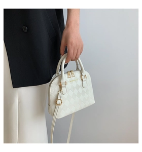 Close-up of white shell-shaped handbag featuring quilted texture and gold-tone zippers