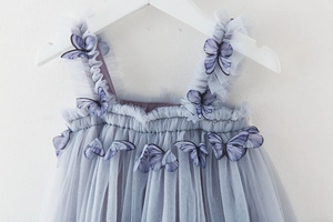 Detail of blue tulle toddler dress featuring 3D butterfly appliques and sequin mesh