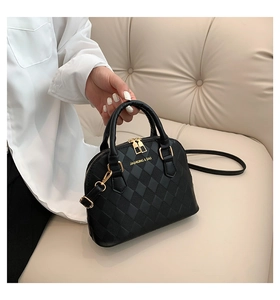 Close-up of black quilted PU leather shell bag with gold logo and dual metal zippers