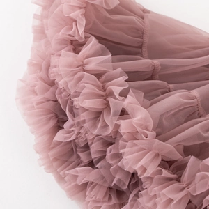 Macro du tissu en tulle rose poudré montrant la texture plissée d'une jupe princesse