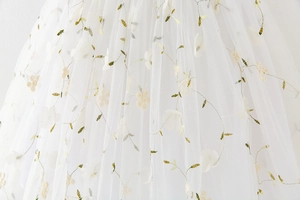 Detail of white tulle fabric with green vine embroidery and 3D floral appliques for girl dress