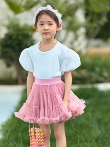 Girls sweet tutu skirt outfit with white puff sleeve t-shirt on a green grass background