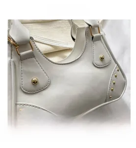 Dettaglio ravvicinato della borsa in ecopelle bianca con borchie dorate decorative laterali