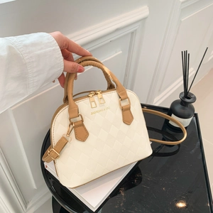 White quilted shell bag with brown handle and gold hardware shown in a lifestyle setting