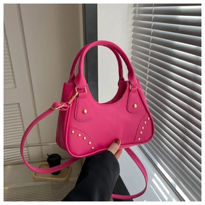 Borsa rosa acceso con rivetti dorati che mostra la trama del materiale e la tracolla