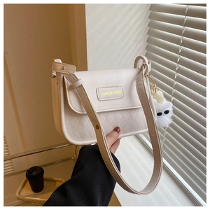 Detail of cream white quilted PU leather crossbody bag with cute plush monster charm