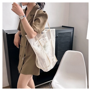 Detalle del bolso de malla beige que muestra el tejido transpirable y la bandolera