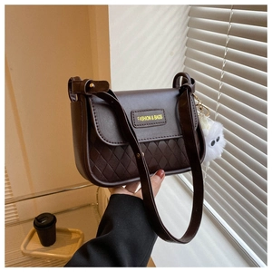 Detail of dark brown quilted shoulder bag with plush ball and metal buckle accent