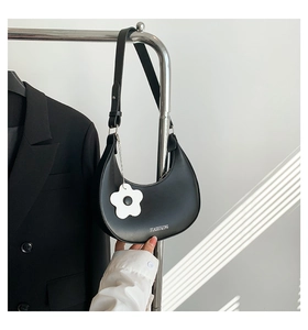 Détail du sac hobo en PU noir avec breloque fleur et ombre rayée artistique