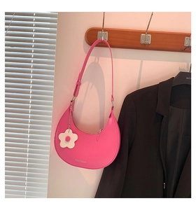 Detail der rosa halbmondförmigen Tasche mit weißem Blumenanhänger und Schnalle