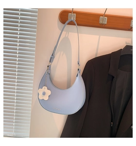 Detail der hellblauen Satteltasche mit weißem Blumenanhänger an einem Holzhaken