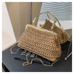 Detail der beigen Strohtasche mit floralen Metallgriffen und goldener Kette