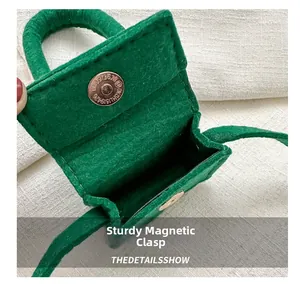 Detail view of the secure magnetic clasp and interior space of this green felt mini bag