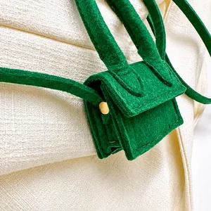 Macro shot of green felt mini bag showing fine stitching and gold metallic hardware
