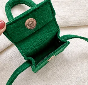 Close-up of green felt mini bag featuring a golden magnetic snap closure and soft interior