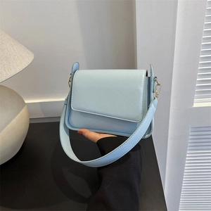 Minimalist light blue crossbody bag with wide strap and gold hardware accents