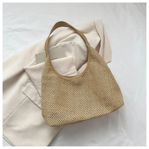 Detail of woven straw tote bag featuring brown leather straps and intricate mesh texture