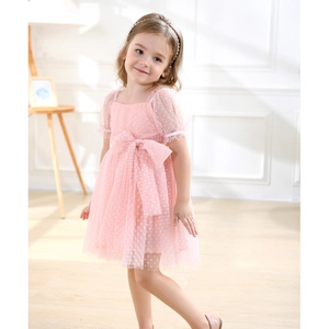 Close-up of pink polka dot tulle fabric with a large bow detail on a girl's dress