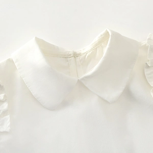 Close-up of white cotton girl shirt featuring Peter Pan collar and ruffle details