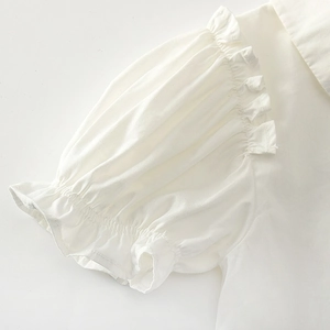 Detailed close-up of white bubble sleeves with delicate ruffle trim and cotton fabric texture