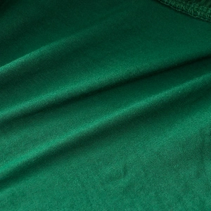 Close-up of dark green tutu skirt fabric showing fine texture and clean hemline stitching