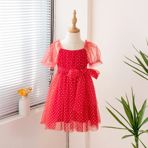 Detail of red tulle girl dress with white polka dots and large waist bow decoration