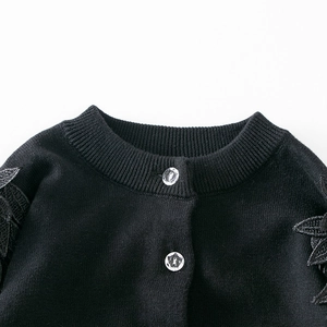 Detailansicht der schwarzen Strickjacke mit geripptem Ausschnitt und Stern-Knöpfen