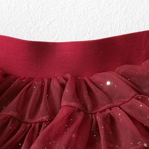 Detailed close-up of red tutu skirt featuring multi-layer glitter mesh and elastic waistband