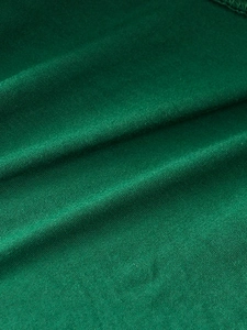 Close-up of deep green knit fabric texture with soft ripples and thick material feel