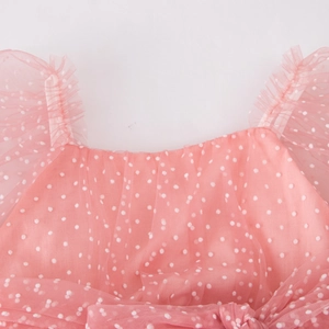 Close-up of pink tulle girls dress featuring white flocked polka dots and ruffle shoulders