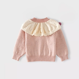 Detailed view of pink knitted girl's sweater with colorful specks and large ruffle collar