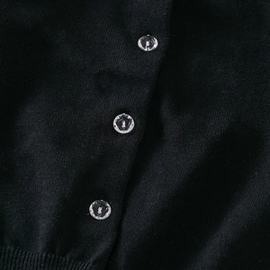Detailaufnahme der schwarzen Strickjacke mit transparenten Knöpfen und Rippstricksaum