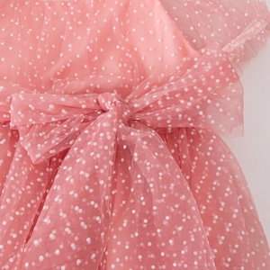 Close-up of pink tulle girls' dress with white polka dots and a layered waist bow