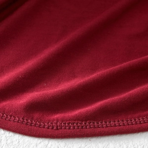Macro shot of red knit fabric texture and double needle lockstitch hem on the cardigan