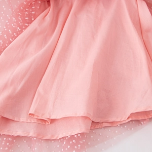 Detail of pink tulle layered fabric with white polka dots and fine stitching on girl's dress
