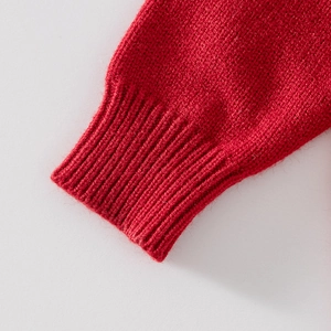 Gros plan d'une manche de cardigan en tricot rouge avec poignet côtelé et laine douce