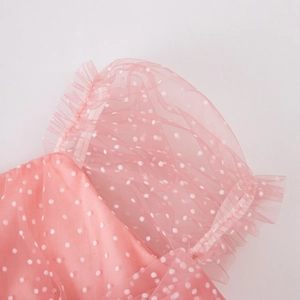 Close-up of pink puff sleeve detail with white tulle polka dots and elegant ruffled edges